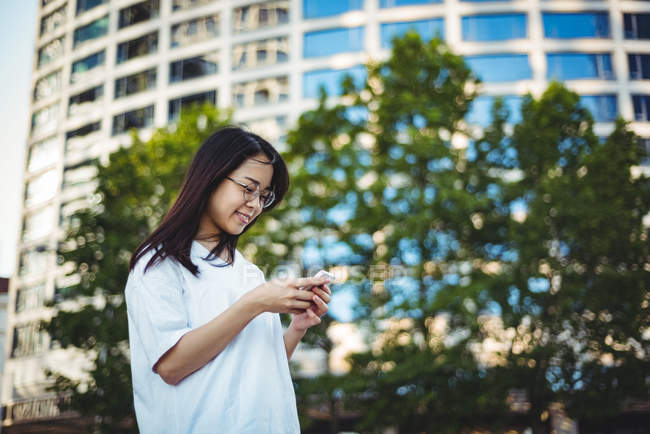 Junge Frau benutzt Handy auf der Straße — Stockfoto