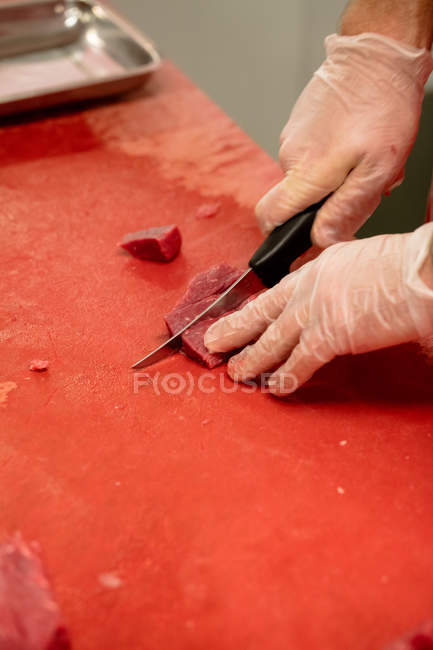 Hands of butcher chopping red meat at butchers shop — Stock Photo