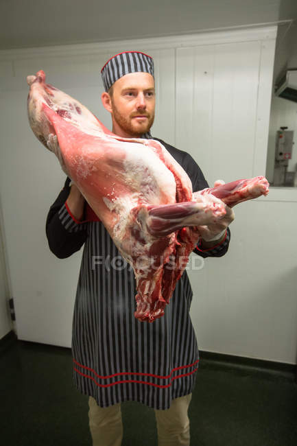 Butcher holding pork carcass in butchers shop — Stock Photo