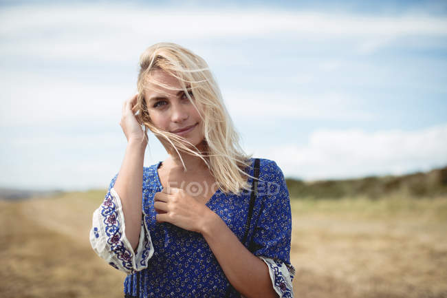 Portrait of attractive blonde woman standing in field — Stock Photo