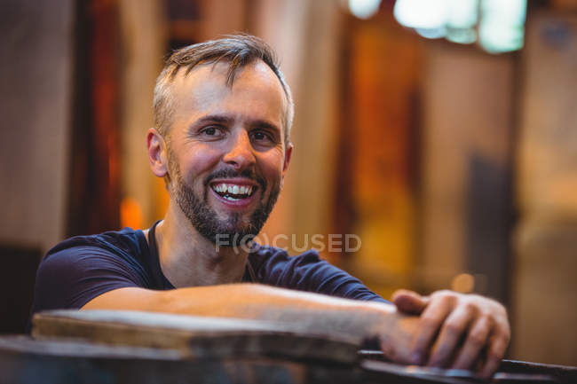 Крупный план улыбающегося стеклодува на стекольном заводе — стоковое фото