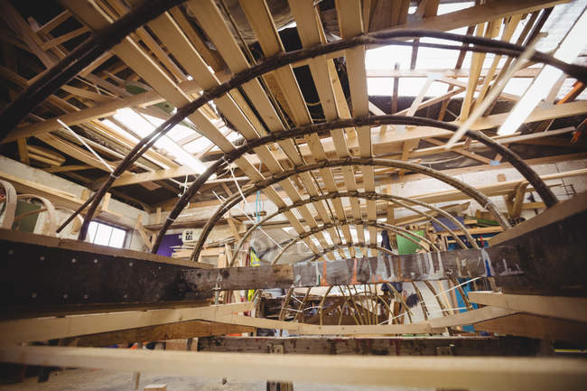Wooden boat under construction in boatyard interior — Stock Photo