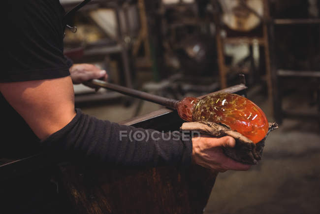 Imagem cortada de Glassblower moldando peça de vidro fundido com pano molhado na fábrica de sopro de vidro — Fotografia de Stock