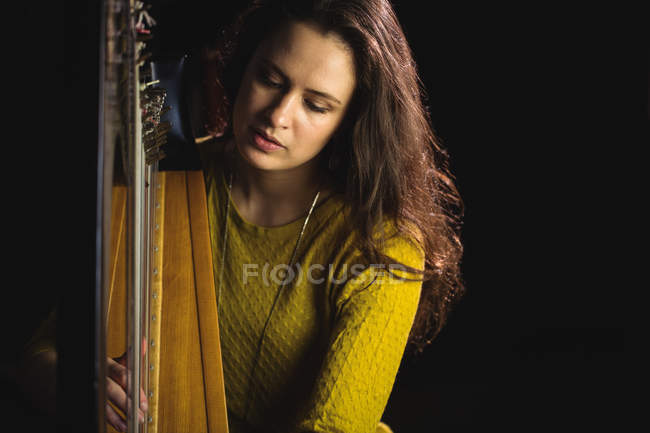 Mulher atenta tocando uma harpa na escola de música — Fotografia de Stock