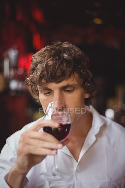 Hombre tomando una copa de vino tinto en el bar - foto de stock