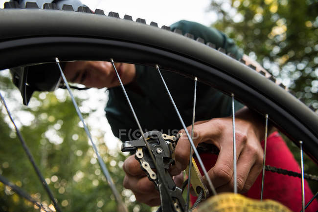 Чоловік-велосипедист ремонтує свій велосипед у лісі в сонячний день — стокове фото