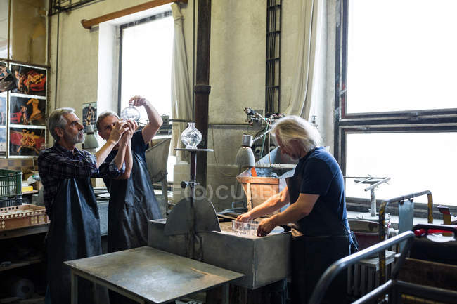 Glassblowers looking at glassware in glassblowing factory — Stock Photo