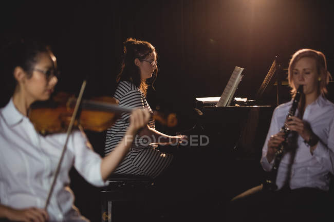 Drei Studentinnen, die in einem Studio Klavier, Klarinette und Geige spielen — Stockfoto