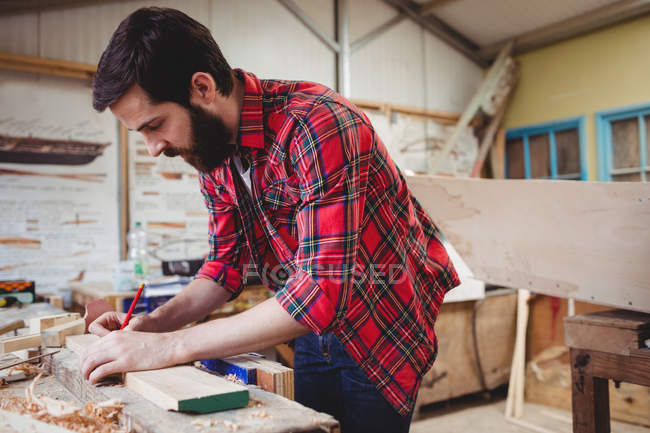 Mann arbeitet auf Bootswerft über Holzplanke — Stockfoto