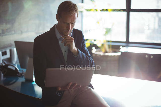 Задуманный бизнесмен, использующий ноутбук в офисе — стоковое фото