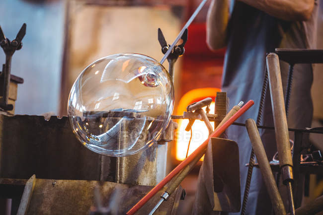 Стеклодувка, формирующая стекло на трубе стеклодувного завода — стоковое фото