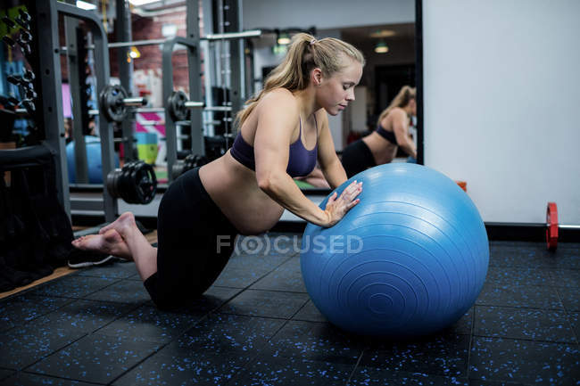 Вагітна жінка займається фітнес-кулькою у спортзалі — стокове фото