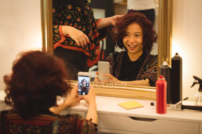 Stylish woman taking mirror selfie at hair salon — Stock Photo