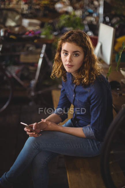 Портрет красивой женщины с помощью мобильного телефона в мастерской — стоковое фото