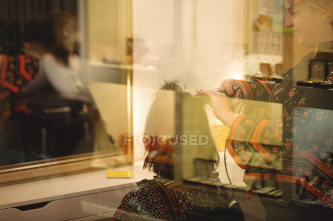 Mulher recebendo cabelo endireitado no salão de cabeleireiro — Fotografia de Stock