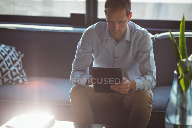 Businessman using digital tablet in office against bright sunlight — Stock Photo