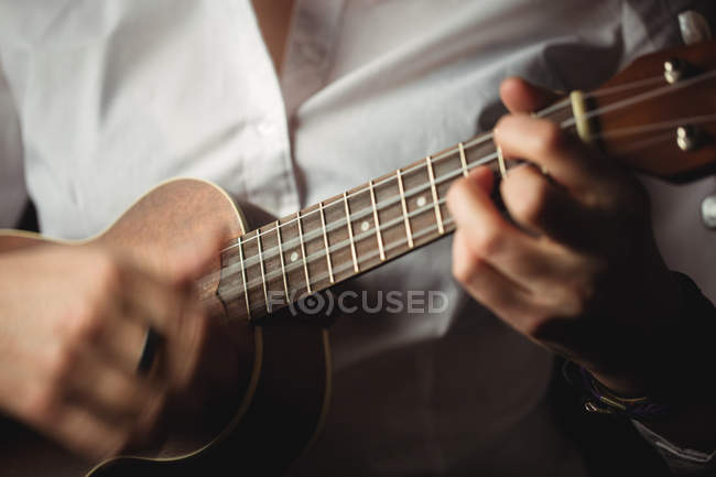 Средняя секция женщины, играющей на гитаре в музыкальной школе — стоковое фото