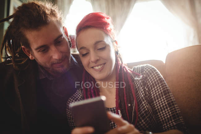 Smiling hipster couple using mobile phone at home — Stock Photo
