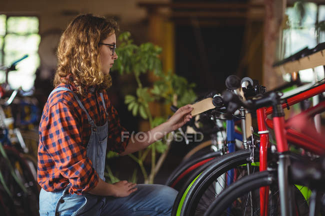 Mecânico examinando uma bicicleta na oficina — Fotografia de Stock