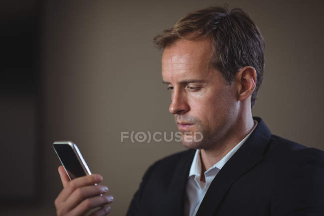 Бизнесмен использует свой мобильный телефон в офисе — стоковое фото