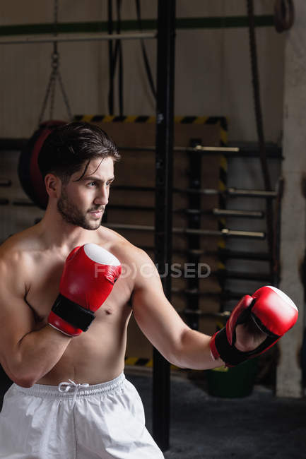 Boxeador sin camisa practicando boxeo en gimnasio - foto de stock