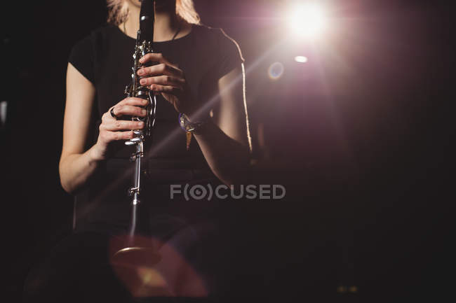 Sección media de una estudiante tocando el clarinete en un estudio - foto de stock