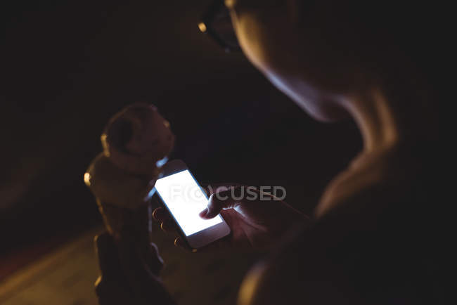 Крупним планом жінка використовує мобільний телефон, маючи морозиво вночі — стокове фото