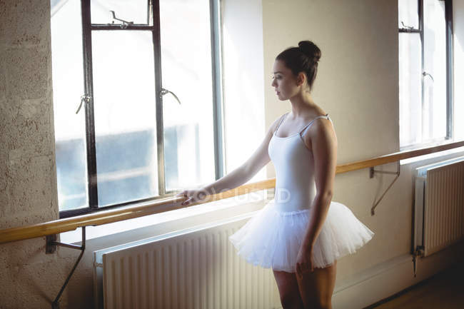 Балерина холдингу бар в студії і, дивлячись на вікна — стокове фото