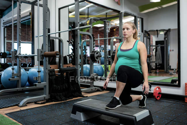 Pregnant woman performing exercise in gym — Stock Photo