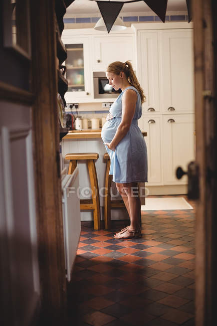 Вид збоку Вагітна жінка стоїть на кухні вдома — стокове фото