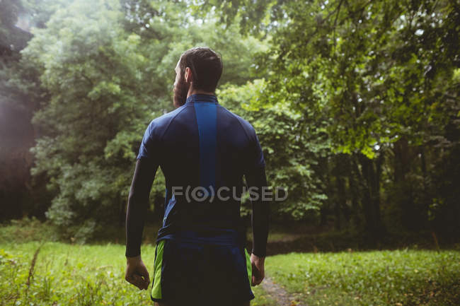 Вид сзади на спортсмена, стоящего в лесу — стоковое фото