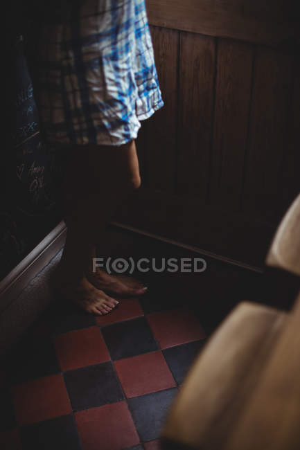 Baixa seção de mulher de pé na porta em casa — Fotografia de Stock