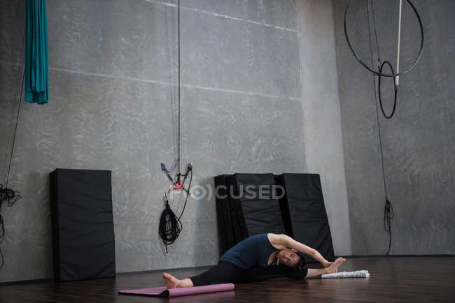 Female gymnast performing stretching exercise in fitness studio — Stock Photo