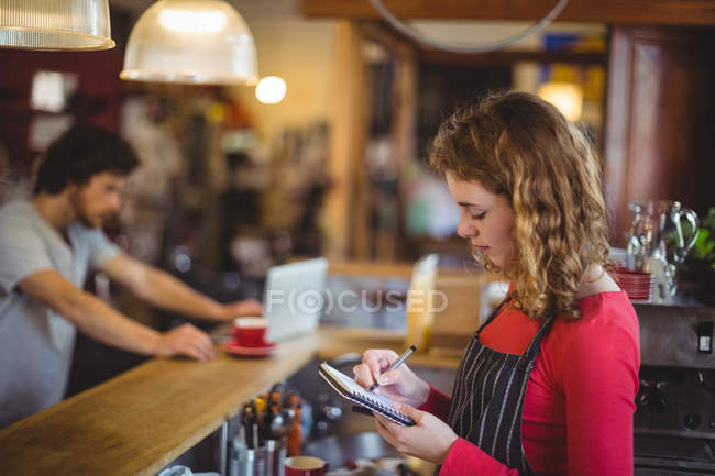 Frau schreibt in Café an Fahrradgeschäft an Tagebuch — Stockfoto