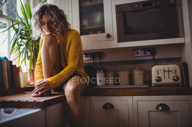 Hermosa mujer sentada en la cocina en casa - foto de stock