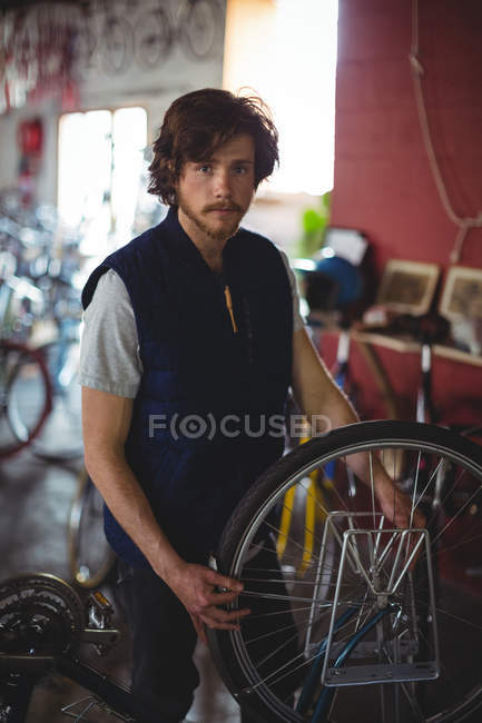 Retrato do mecânico que examina a bicicleta na oficina — Fotografia de Stock