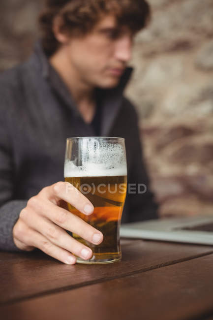 Mann trinkt Bier, während er Laptop an Bar benutzt — Stockfoto
