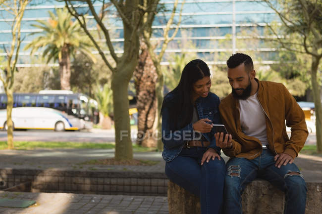 Romantic couple using mobile phone in city — Stock Photo