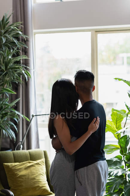 Couple regardant par la fenêtre dans le salon à la maison — Photo de stock