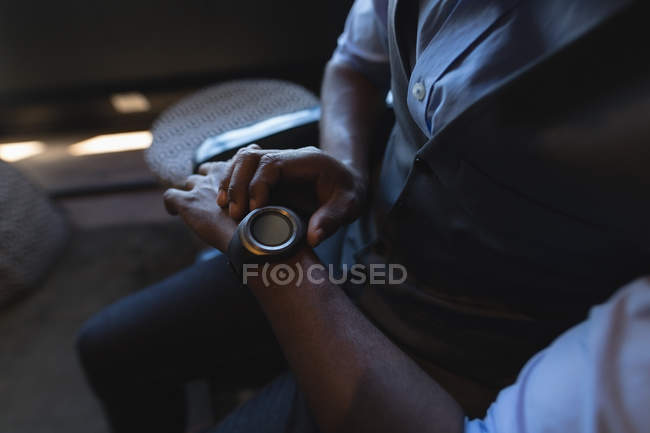 Mid section of businessman using smartwatch in office — Stock Photo