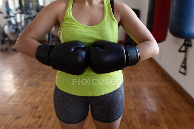 Mid section of female boxer standing with boxing gloves in fitness studio — Stock Photo