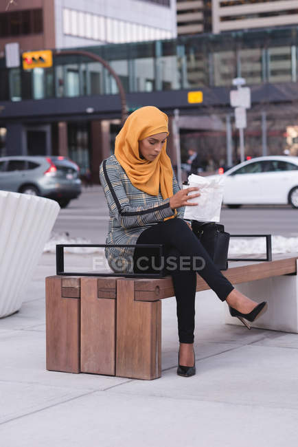 Hijab mujer sentado en el banco en la ciudad - foto de stock