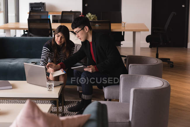 Виконавці обговорюють ноутбук в офісі — стокове фото