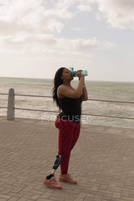 Вид сбоку женщины-инвалида, пьющей воду на набережной — стоковое фото