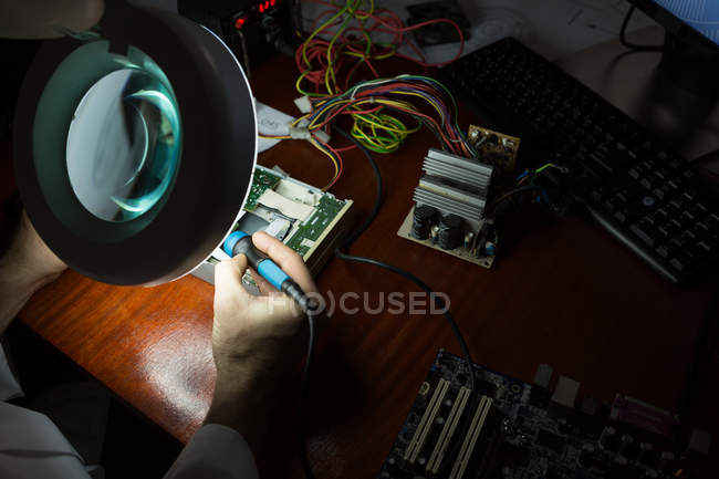 Robotics engineer assembling circuit board at desk in warehouse — Stock Photo