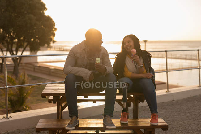 Счастливая пара с мороженым на скамейке для прогулок — стоковое фото