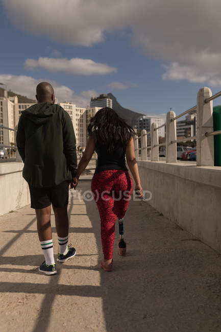 Rear view of couple holding hands and walking on promenade — Stock Photo