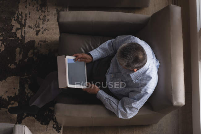 La sobrecarga del hombre mayor usando tableta digital en la sala de estar en casa - foto de stock