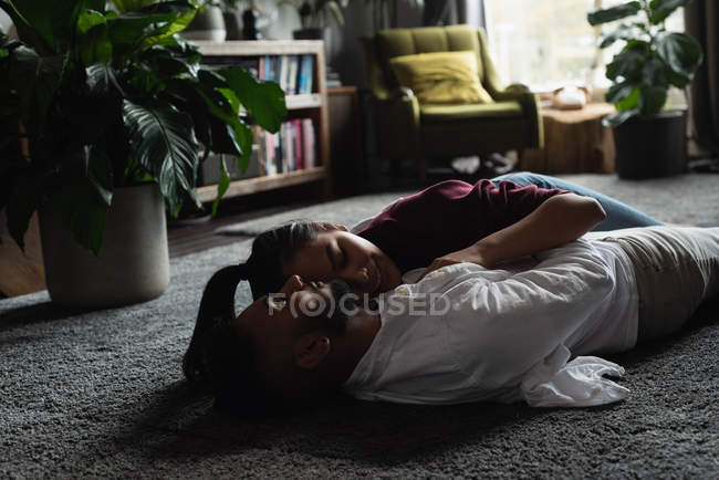 Pareja relajándose en el suelo en la sala de estar en casa - foto de stock
