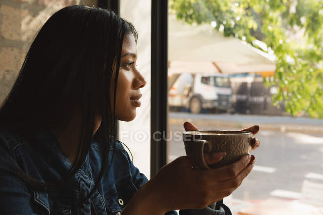 Vista lateral de la mujer tomando café en la cafetería - foto de stock